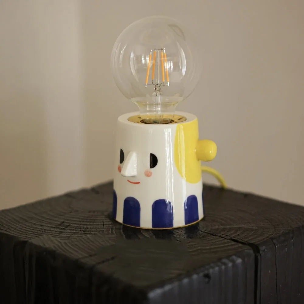 Handmade ceramic table lamp with ball headlight design on a bedside table