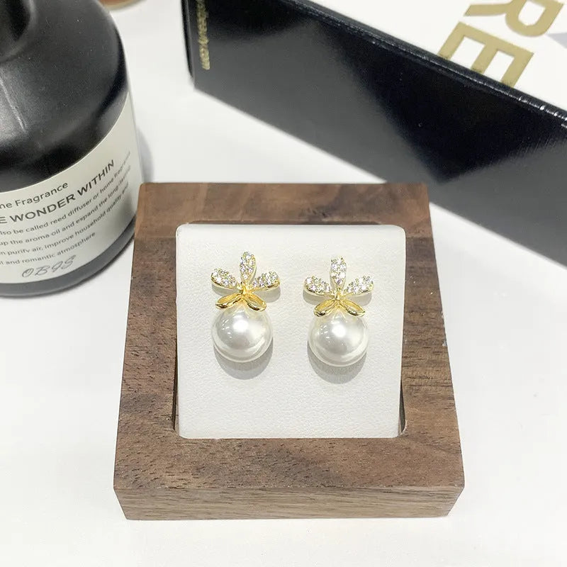 Pair of pearl flower drop earrings in gold and silver finishes on a light background