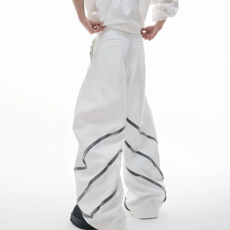 Men's black and white deconstructed trousers with metal striped rivets and front pleats.