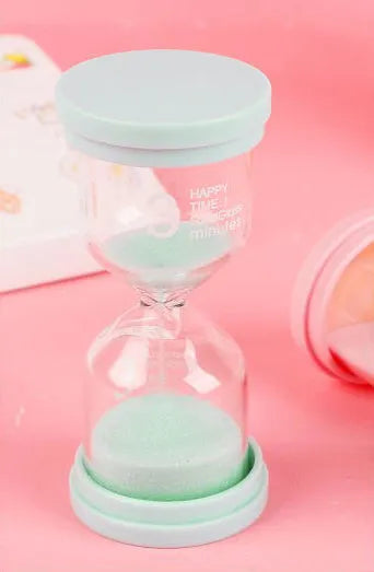 Handmade glass sand timer hourglass in blue on a plain background.