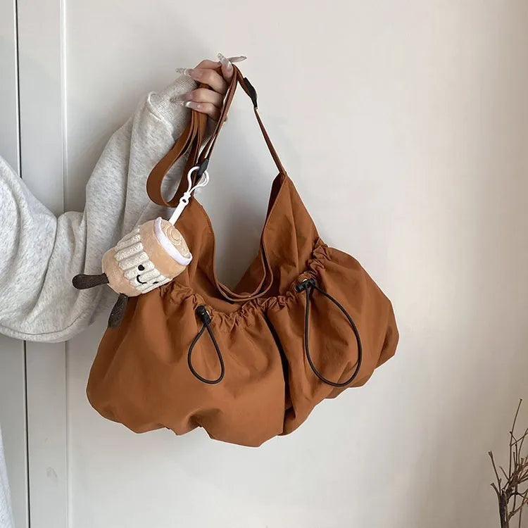 Ultra-light pleated foldable crossbody bag in beige, showing split pocket and crossbody strap.