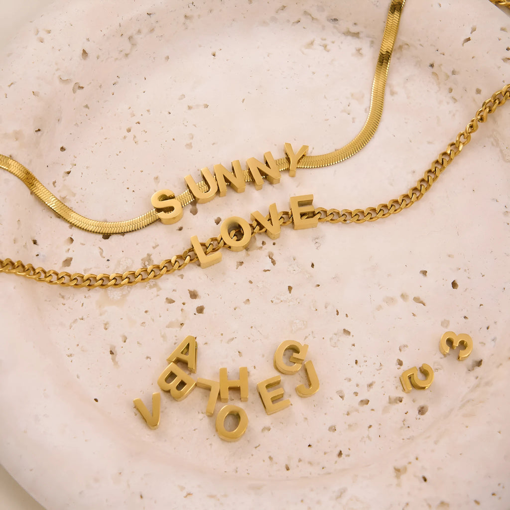 Gold and silver titanium steel initial number necklace with alphabet and number pendants on a 40.5cm chain.