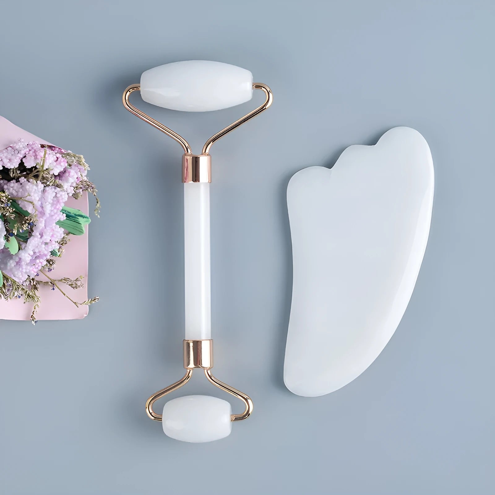 Natural white jade double-headed facial roller and gua sha scraping board set on a plain background.