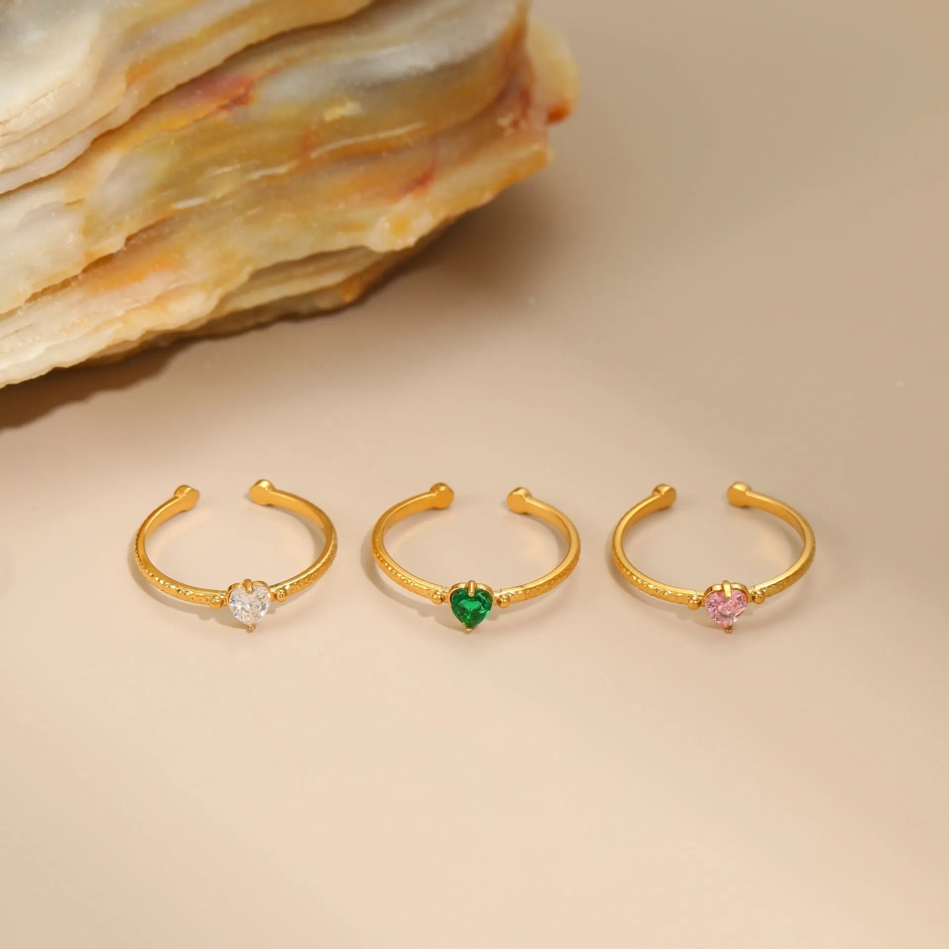 Open-ended stainless steel ring with a geometric heart shape and inlaid green zircon stone.