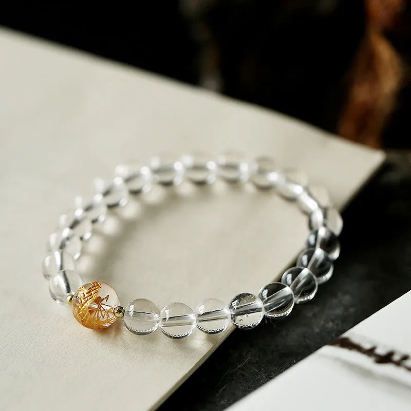 Geometric obsidian and white crystal beaded bracelet with golden dragon charm on a wrist.