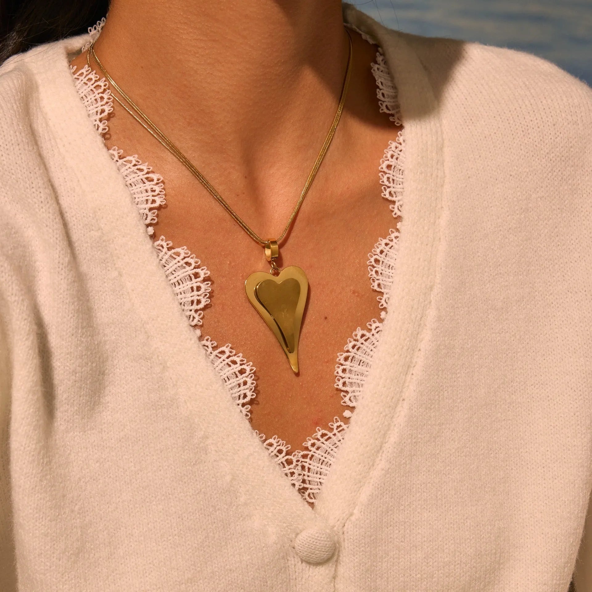 Close-up of a women's stainless steel necklace with a double heart snake bones chain and a geometric pendant.