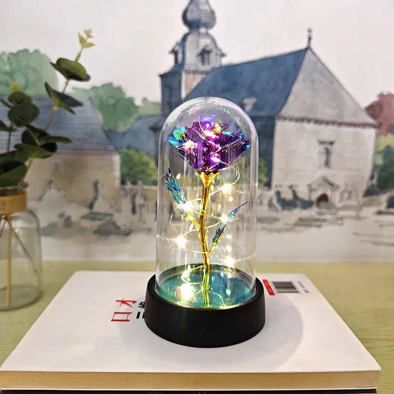 Small decorative night lamp with glass cover, plastic flower, and black base on a pink box.