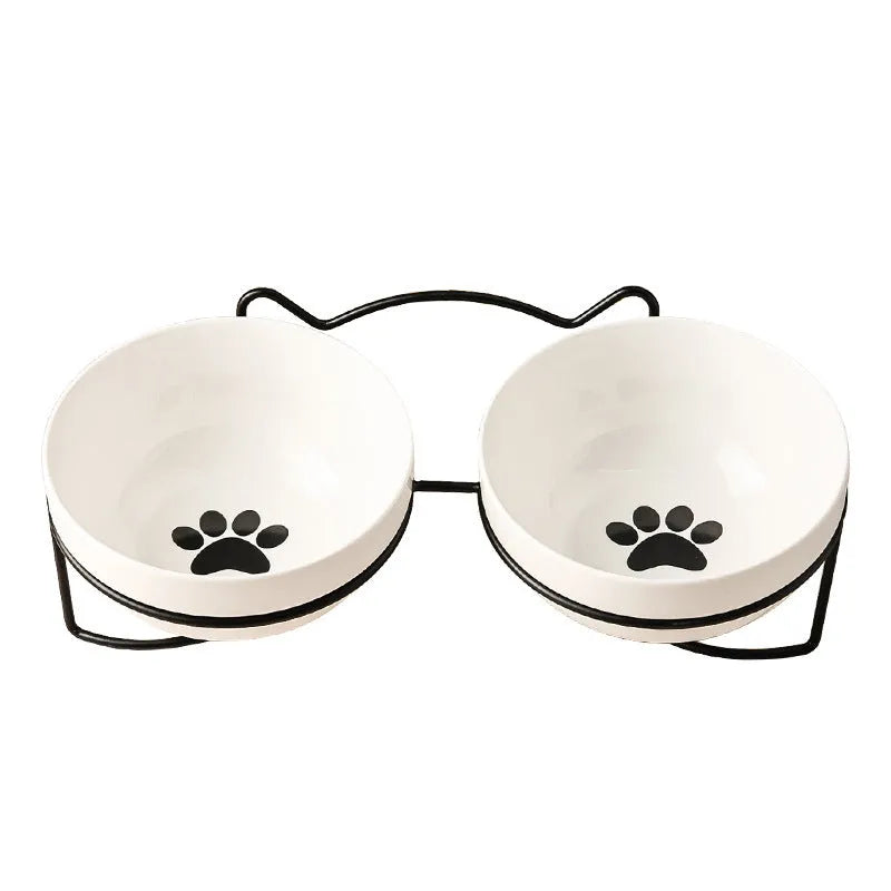 White ceramic cat bowl with cat paw print design on a black iron frame stand