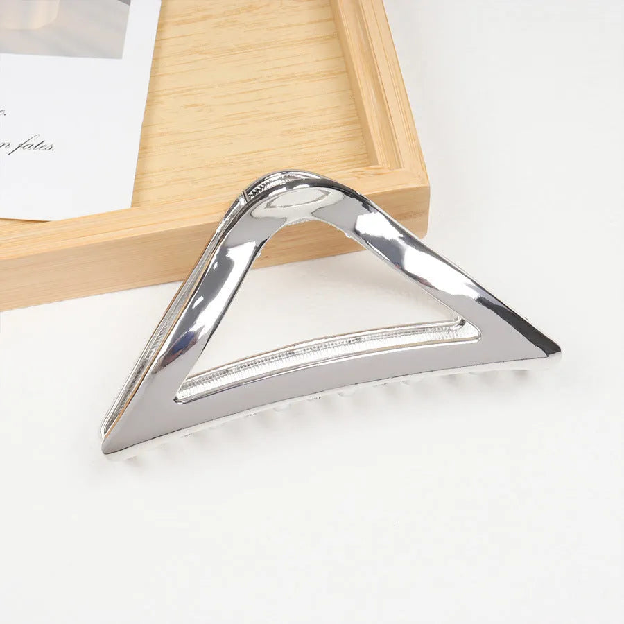 Assorted silver metal hair claws and barrettes including wave, knot, bow, and pearl designs on a white background.