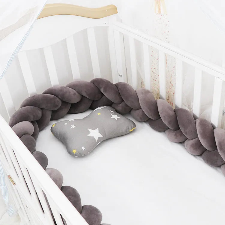Braided knot crib bumper in spandex velvet, shown bending to fit a white wooden cot.