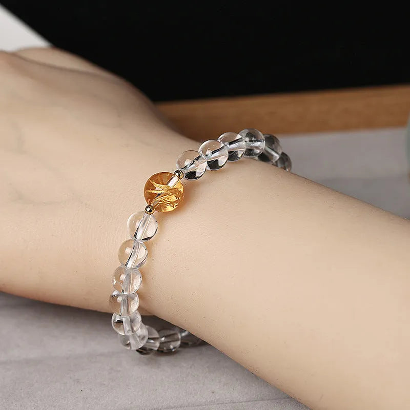 Geometric obsidian and white crystal beaded bracelet with golden dragon charm on a wrist.
