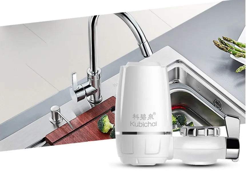 White plastic kitchen tap water filter with ceramic cartridge and universal adapter kit on a counter.