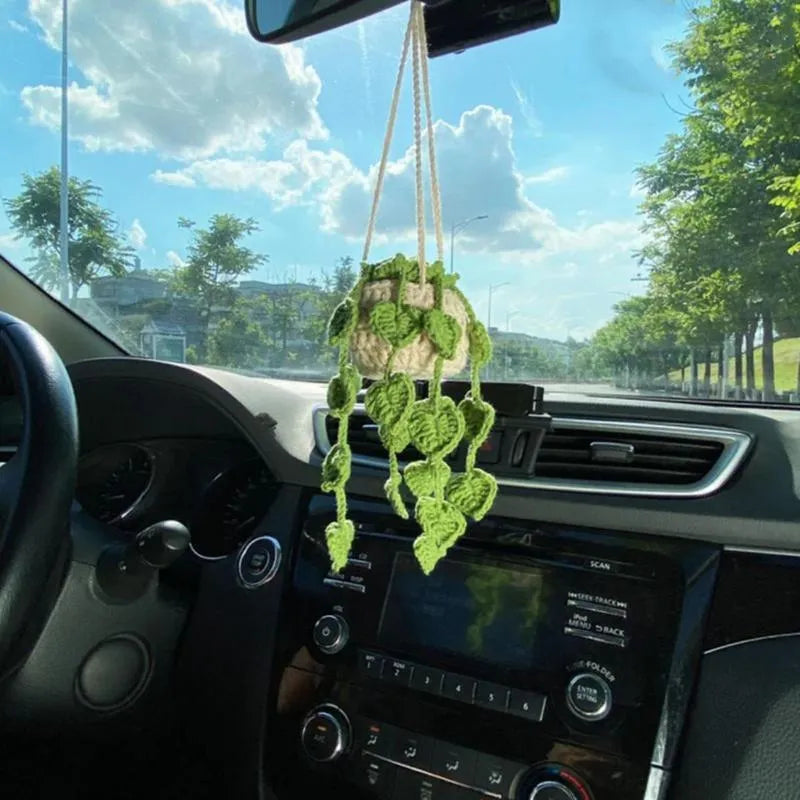 Green and white knitted wool car plant decoration with macramé texture and a white hanging rope.