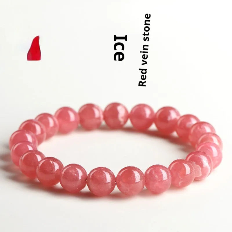 Women's geometric crystal bracelet with red rhodochrosite stone and a Longevity Lock charm on a wrist.