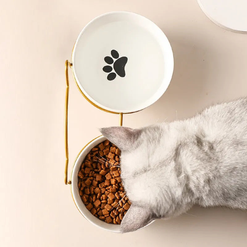 White ceramic cat bowl with cat paw print design on a black iron frame stand