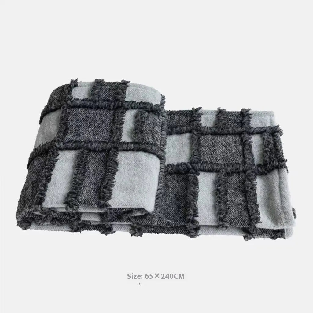 Modern minimalist grey and white plaid bed runner blanket with matching pillowcase and round pillow on a double bed.