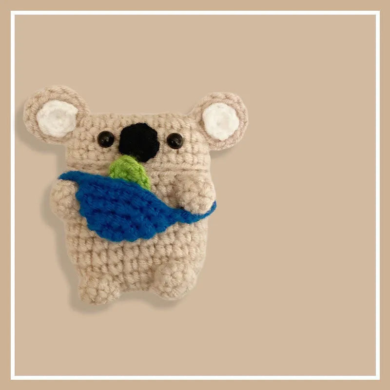 Handmade knitted koala bear backpack cover for Apple Airpods case on a table.