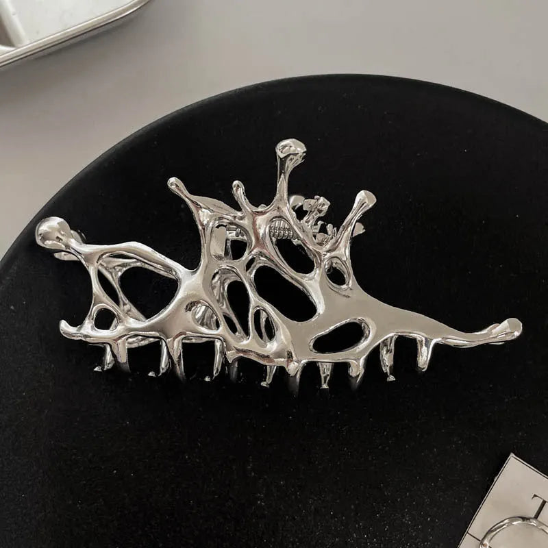 Assorted silver metal hair claws and barrettes including wave, knot, bow, and pearl designs on a white background.