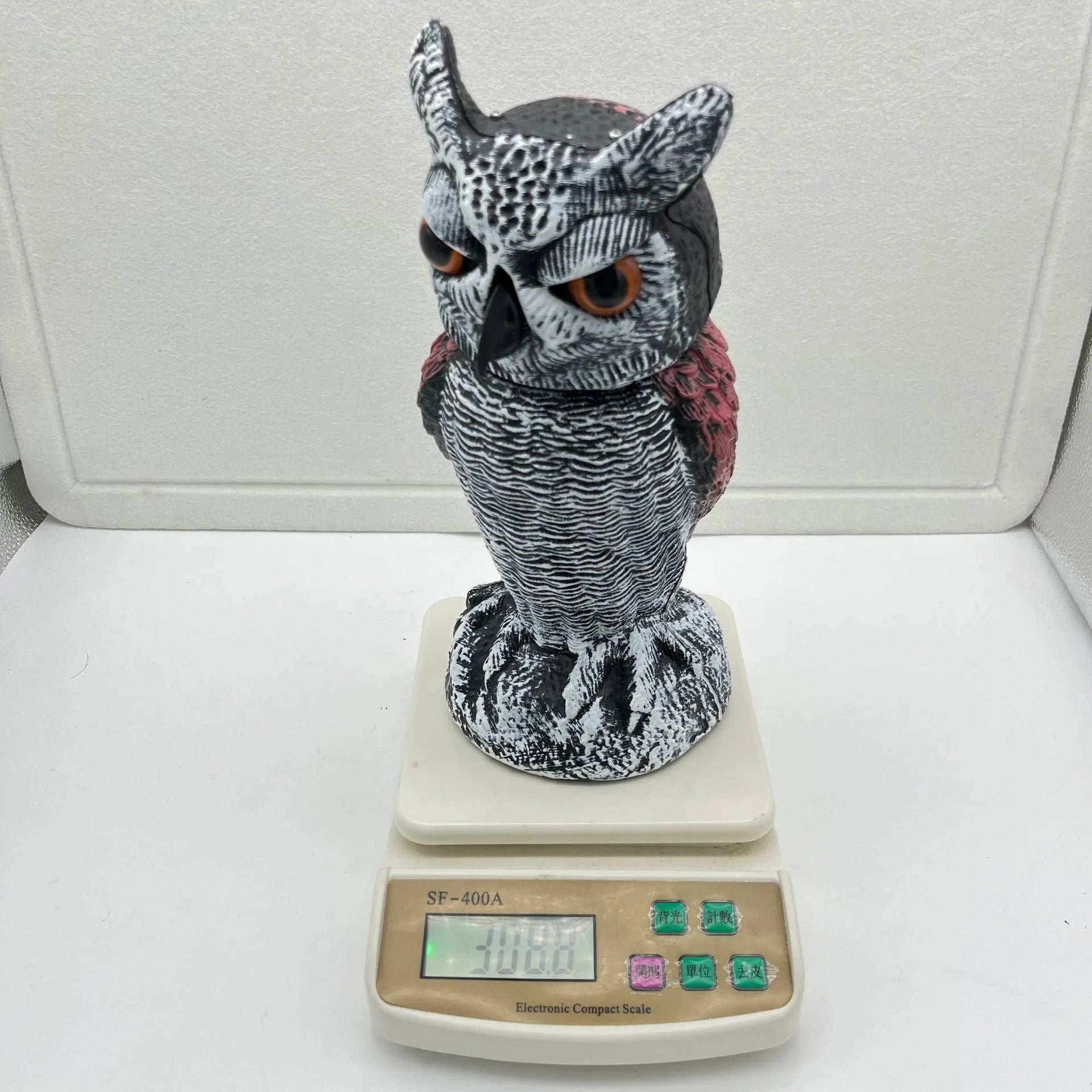 Artificial owl bird scarer decoy with shaking head motion in outdoor setting