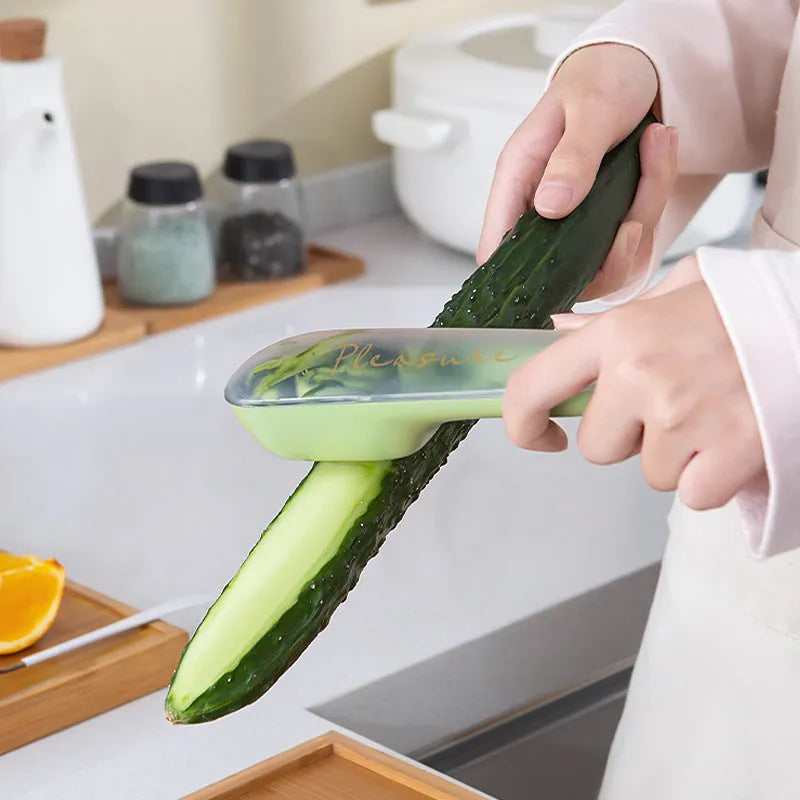 Green vegetable peeler with storage tube, non-slip handle, and hang hole on a kitchen worktop.