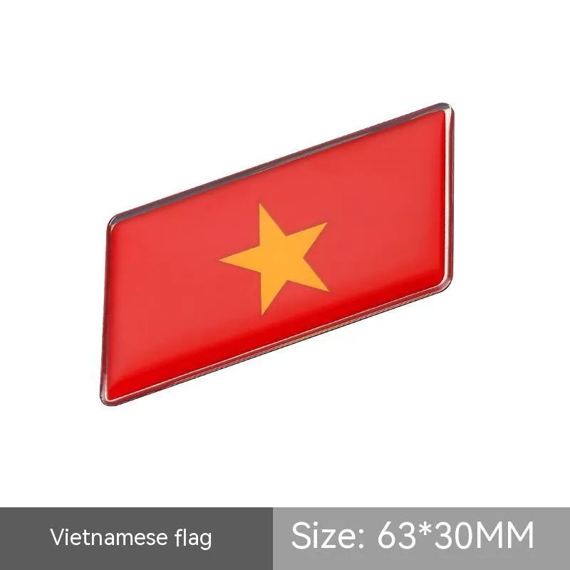 Aluminium parallelogram car sticker showing a national flag design, measuring 6.3 by 3 centimetres.