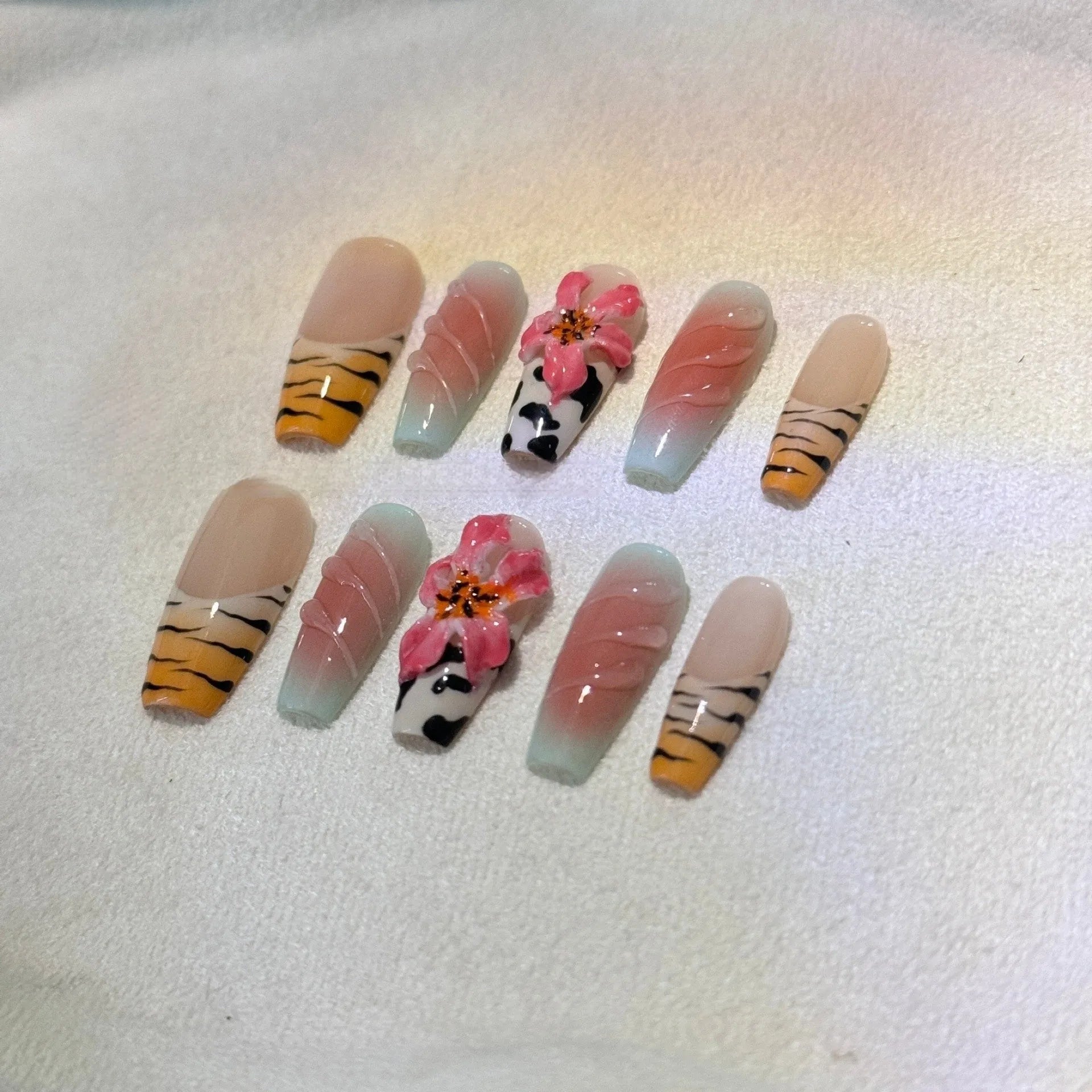 Set of false nails with zebra stripe, lily flower, and leopard print hand carving designs in long, wear-resistant style.
