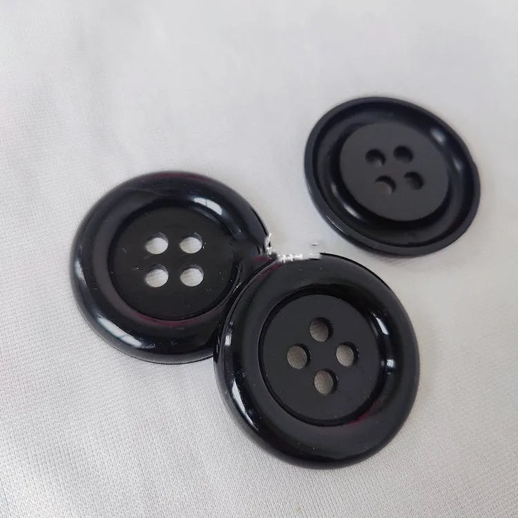 Assortment of oversized round plastic buttons in various colours with four holes.