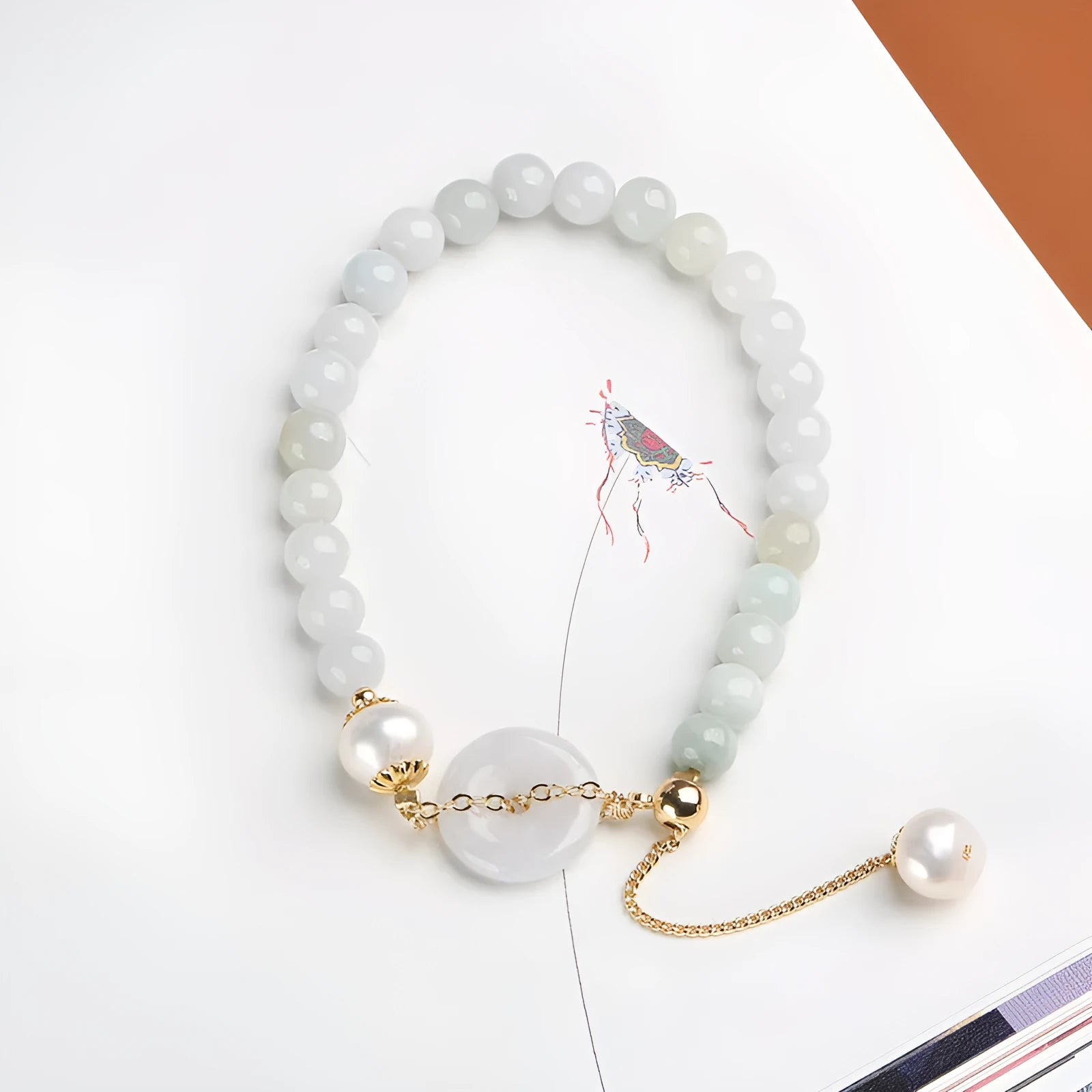 Jade green bracelet with peace buckle fastener and round pearl charms on wrist