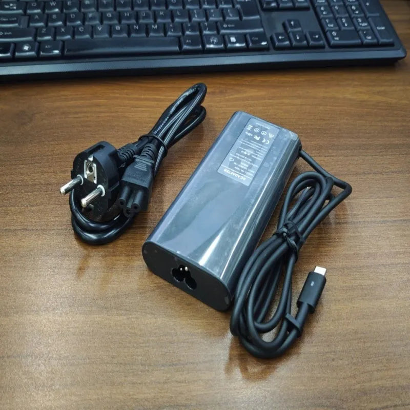 Black 65W USB-C laptop power adapter with set of international plug cords.