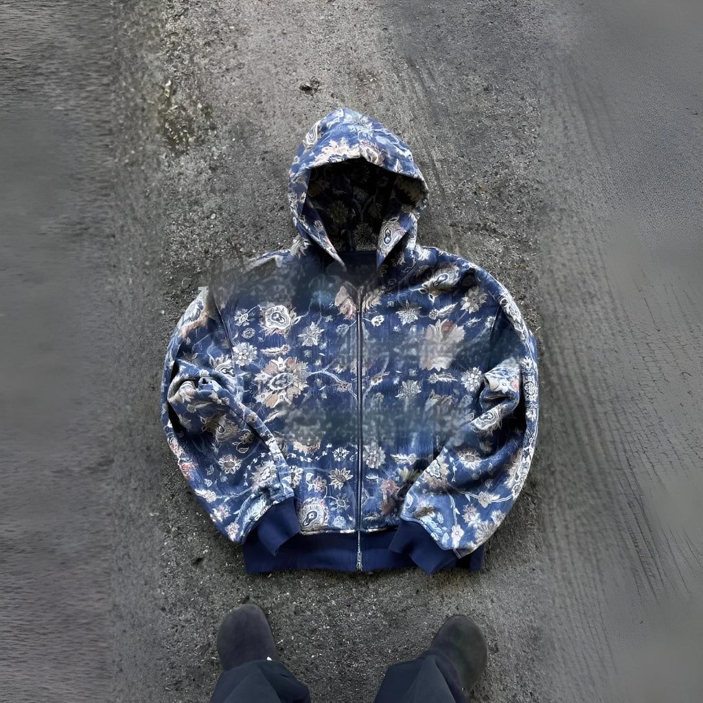 A man's loose-fitting blue hooded zip coat with long sleeves on a hanger.