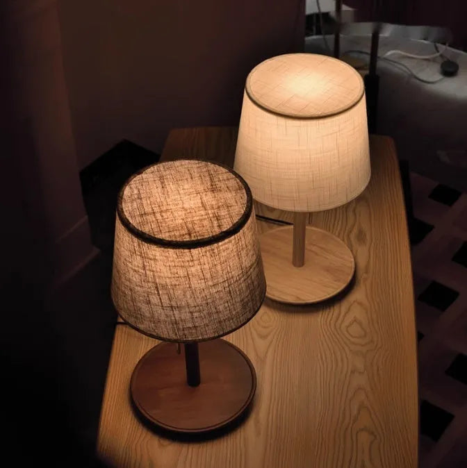 Walnut coloured solid wood bedside table lamp with a white cloth lampshade.