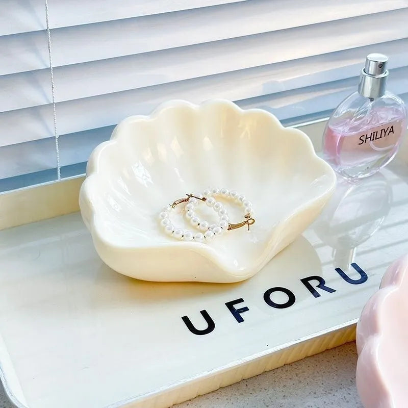 White or pink plastic shell-shaped soap dish with slatted base for bathroom use.