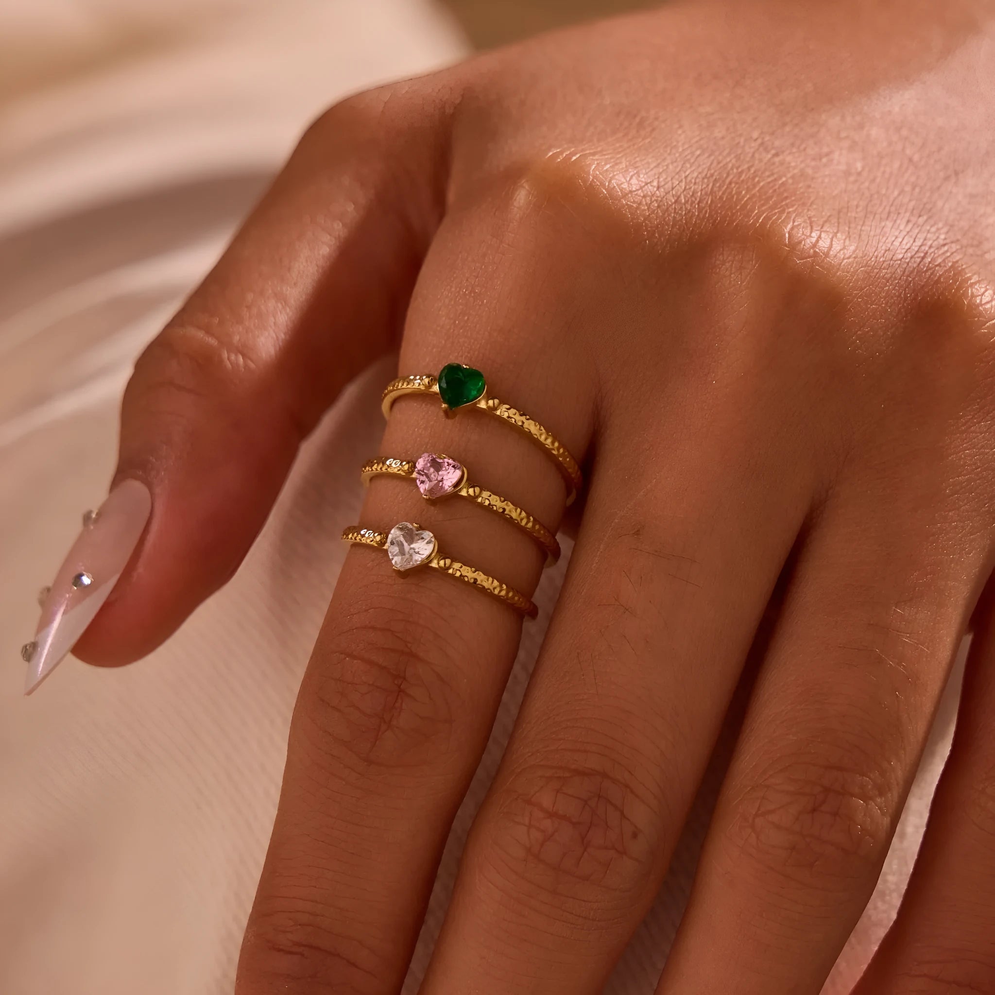 Open-ended stainless steel ring with a geometric heart shape and inlaid green zircon stone.