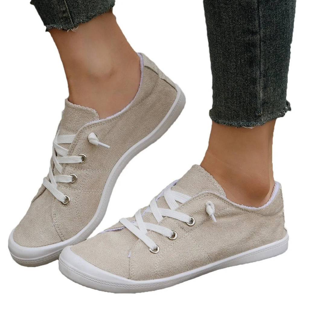 Women's creamy-white low-top fabric sneaker with rubber sole on a neutral background.