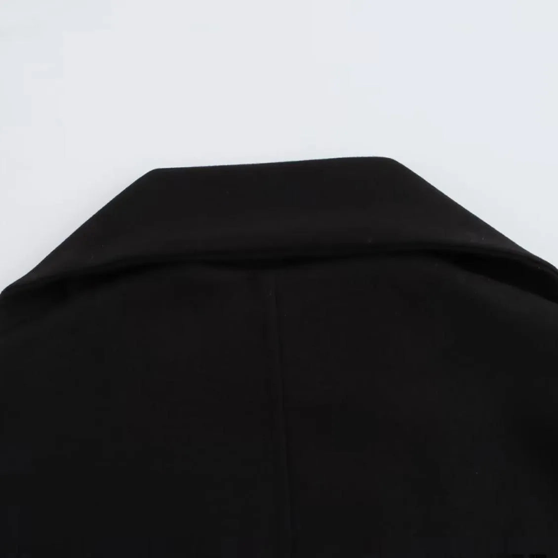 Women's long black polyester winter coat with a fluffy artificial fur collar, shown in a street fashion style.