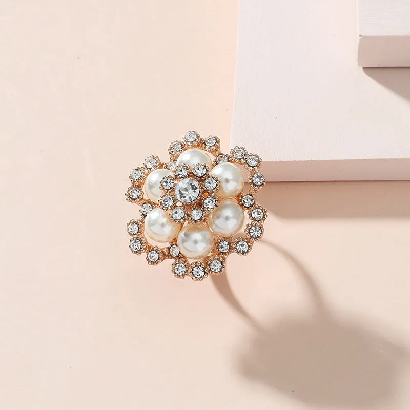 Simple retro fashion ring with pearl inlay and rhinestone flower shape in white KC gold on a flat surface