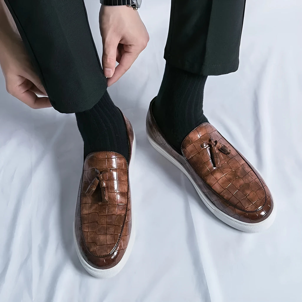 Men's plus size black slip-on sneakers with tassel detail and round toe on a rubber sole.