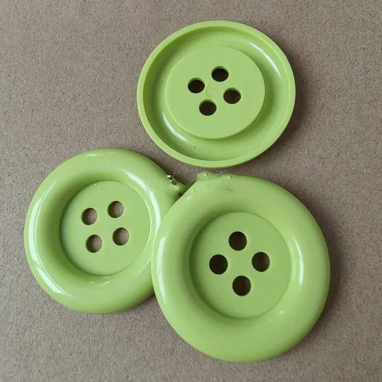 Assortment of oversized round plastic buttons in various colours with four holes.