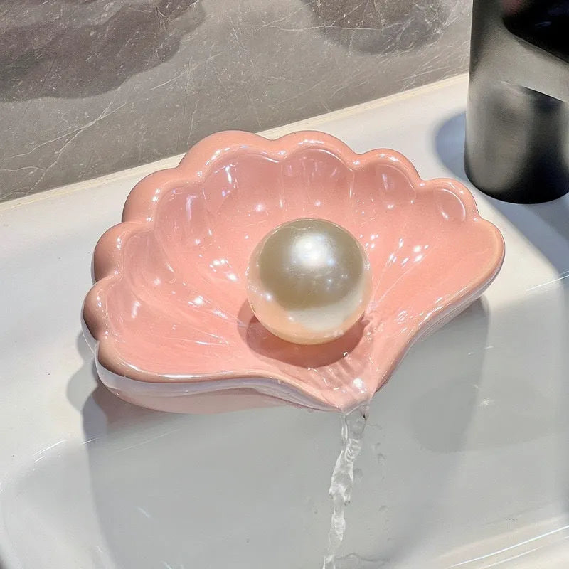 White or pink plastic shell-shaped soap dish with slatted base for bathroom use.