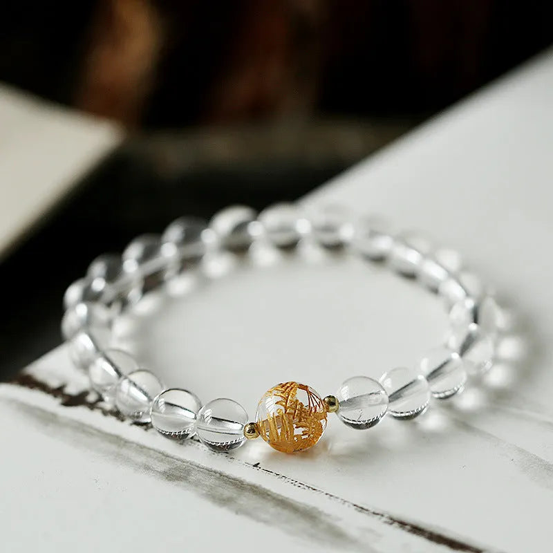 Geometric obsidian and white crystal beaded bracelet with golden dragon charm on a wrist.