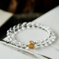 Geometric obsidian and white crystal beaded bracelet with golden dragon charm on a wrist.