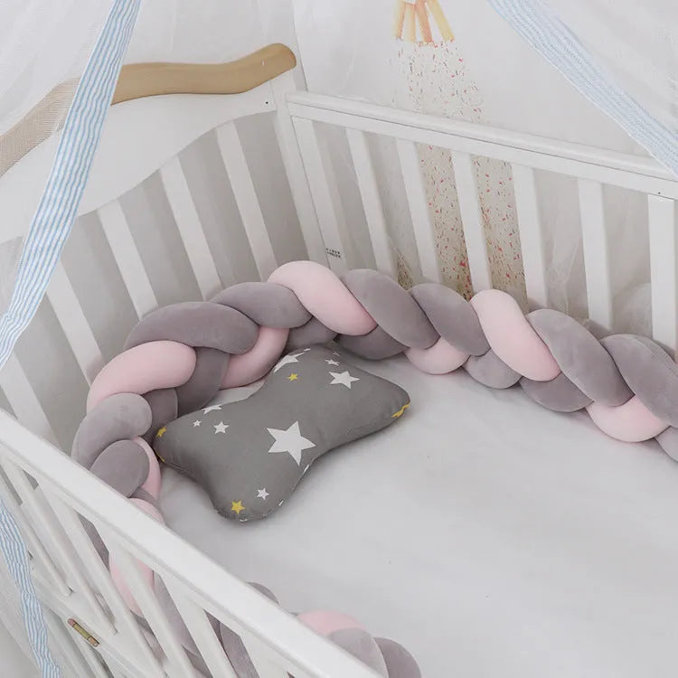 Braided knot crib bumper in spandex velvet, shown bending to fit a white wooden cot.