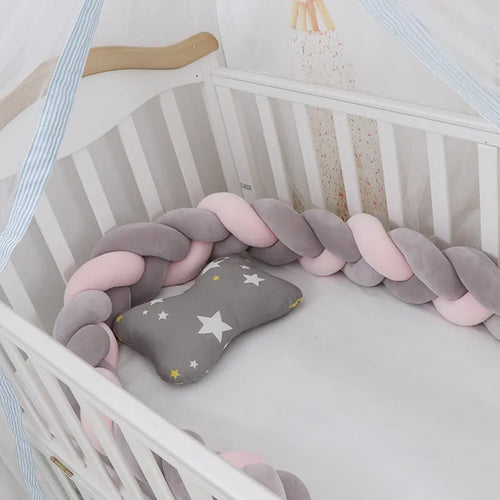 Braided knot crib bumper in spandex velvet, shown bending to fit a white wooden cot.