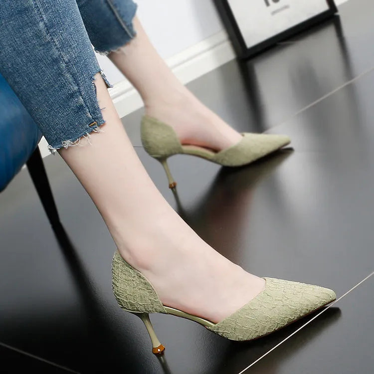 Women's black pointed stiletto high heels with a thin heel on a plain background.