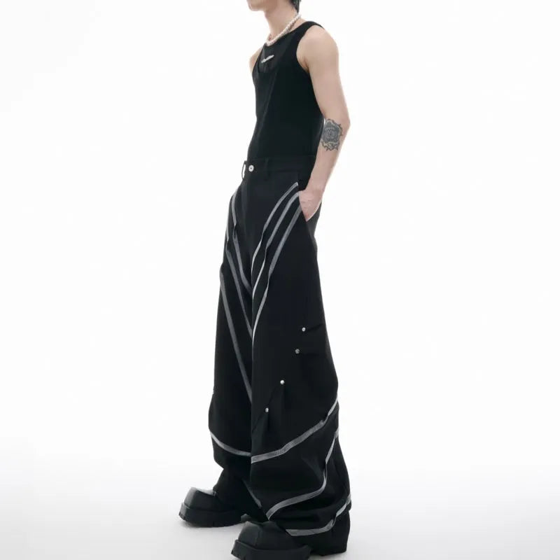 Men's black and white deconstructed trousers with metal striped rivets and front pleats.