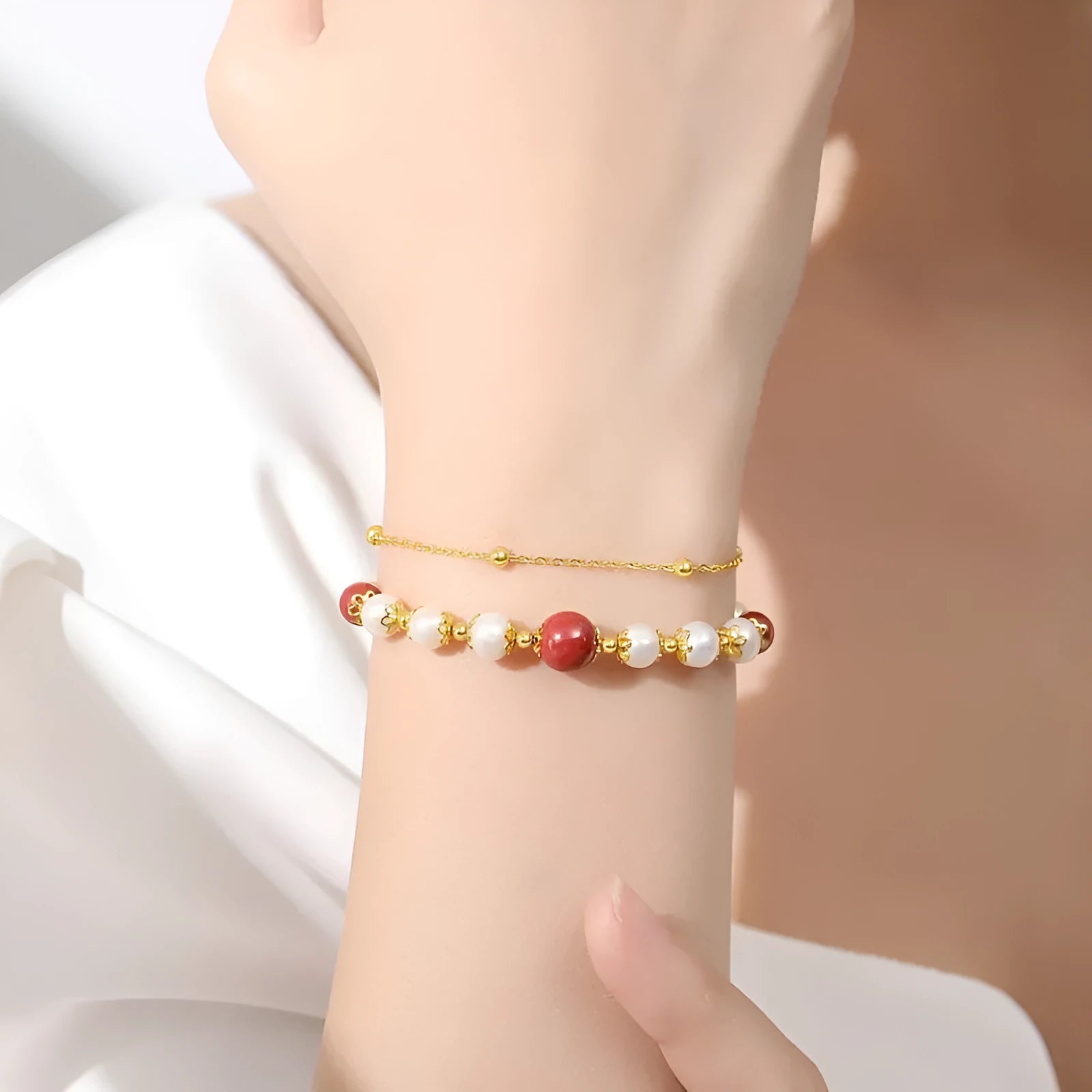 Sterling silver double-layer bracelet with cinnabar red bean and freshwater pearl beads, electroplated finish, geometric bean shape on white background