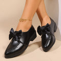 Women's beige loafers with a large decorative bow, showcasing rounded toe and slip-on design.
