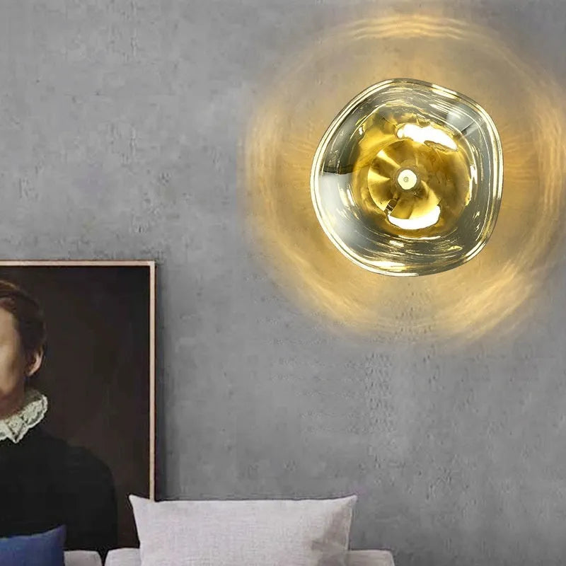 Modern lava wall lamp with acrylic shade in gold finish on a corridor wall emitting warm light