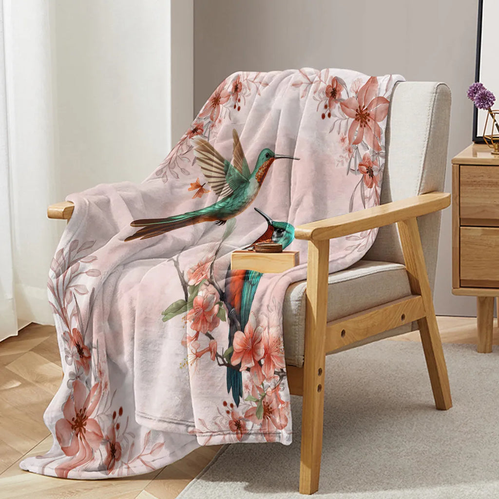 Hummingbird floral fleece throw blanket in pink flannel velvet, shown on sofa with hemmed edges