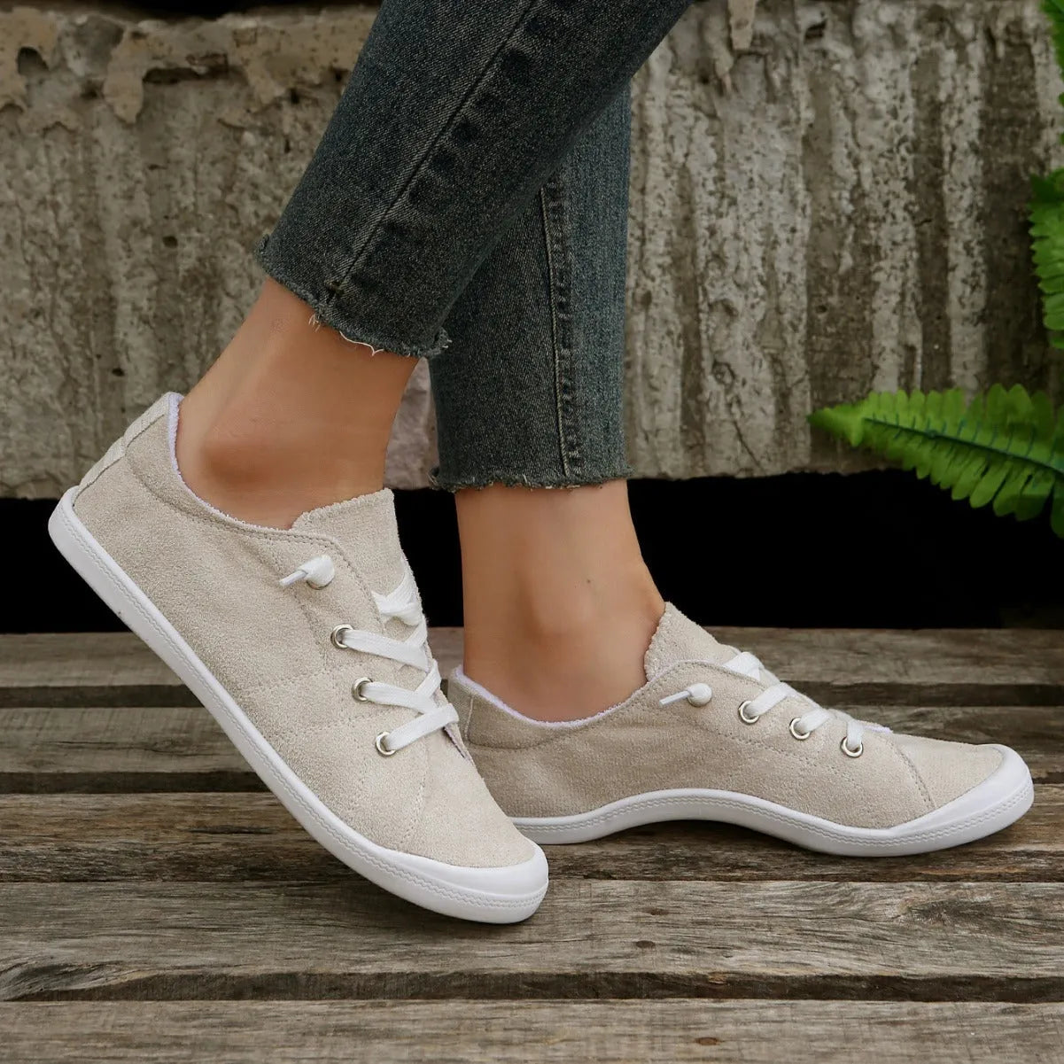 Women's creamy-white low-top fabric sneaker with rubber sole on a neutral background.